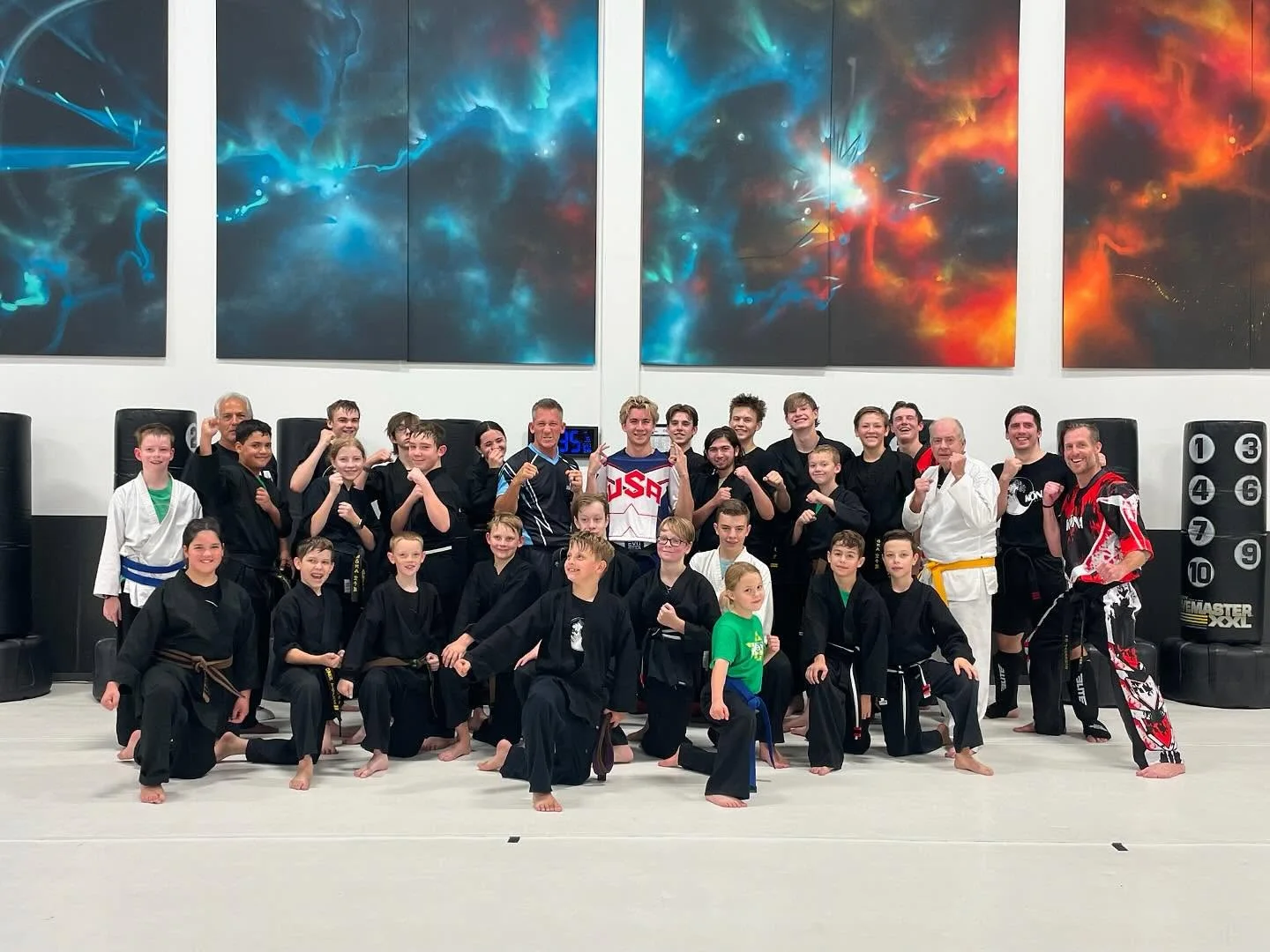 The family of students and instructors gathered together on the training floor in