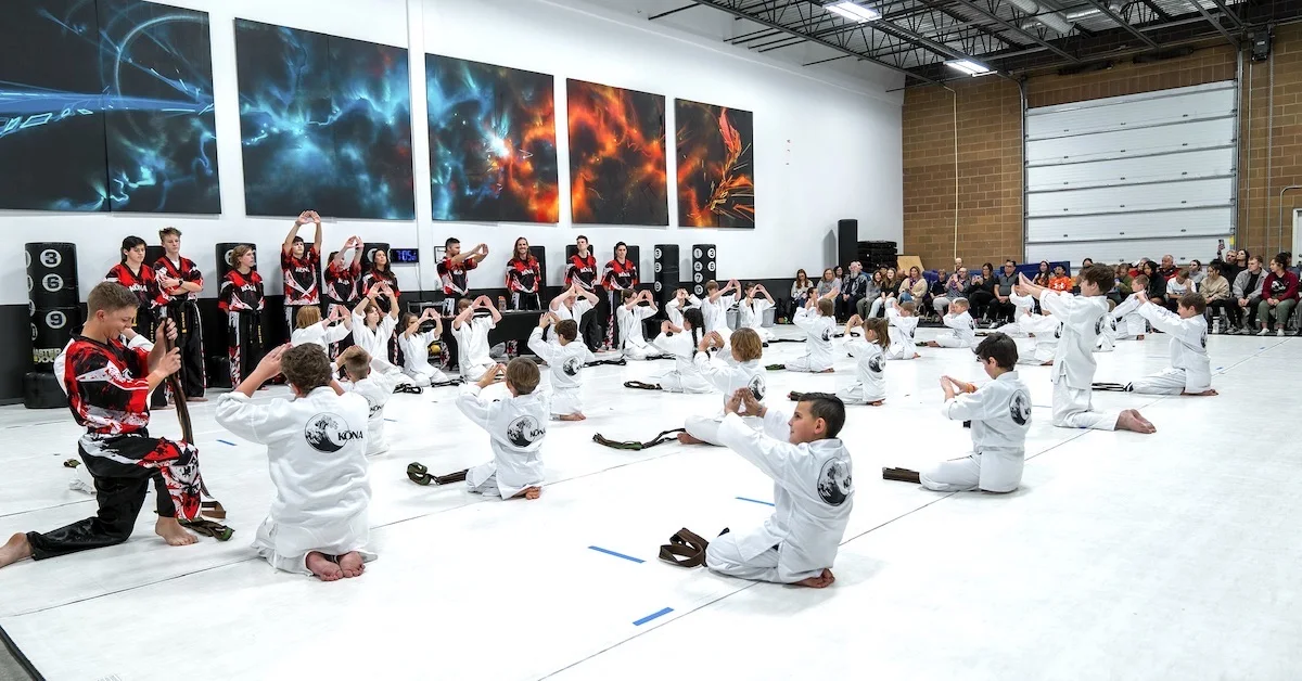 An instructor closely supervising kids karate students on the mat
