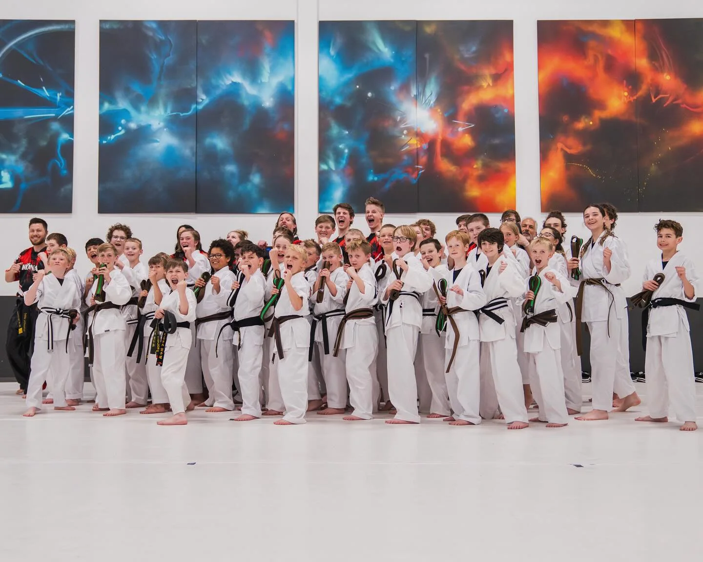 A long line of Kona Karate students in white gis standing across the training floor
