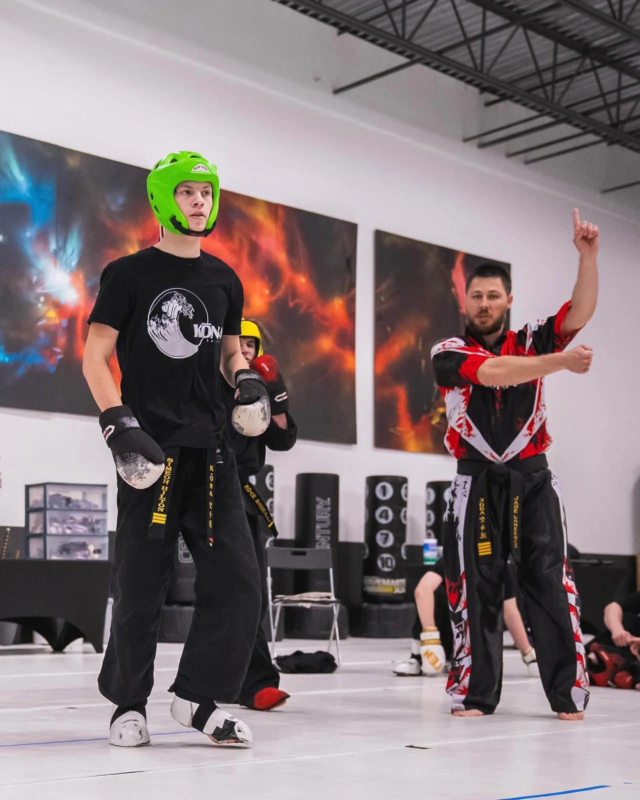 An instructor closely supervising teens karate students on the mat
