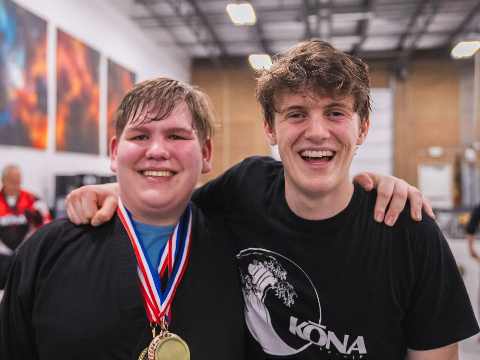 Two Kona Karate students grinning with tournament medals around their necks